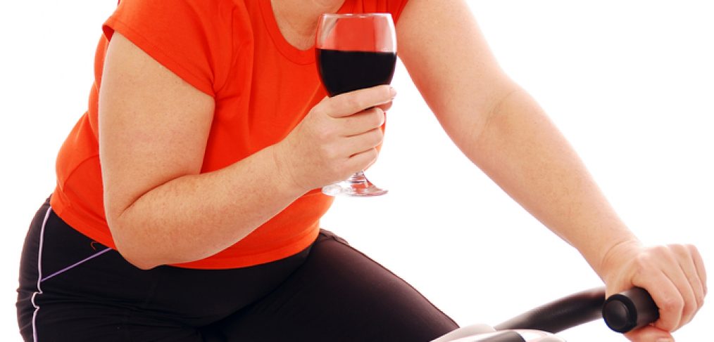 Woman on stationary bike with a glass of red wine