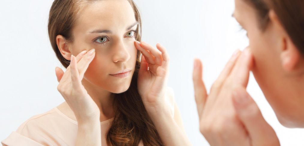 Woman examines her wrinkles in the mirror.