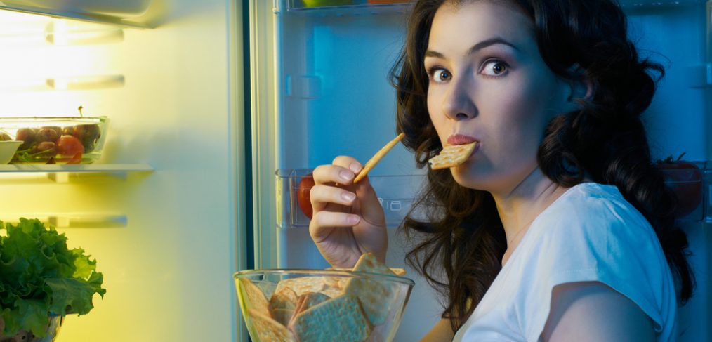 Woman eating a snack at night.