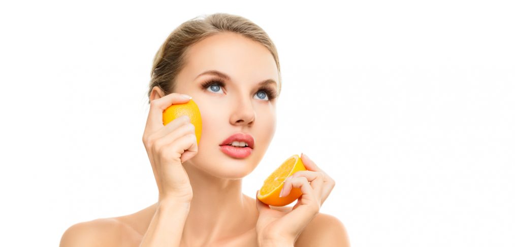 Woman holding an orange close to her face