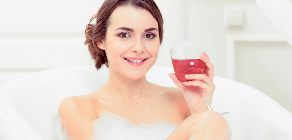 Woman sipping wine while taking a bath