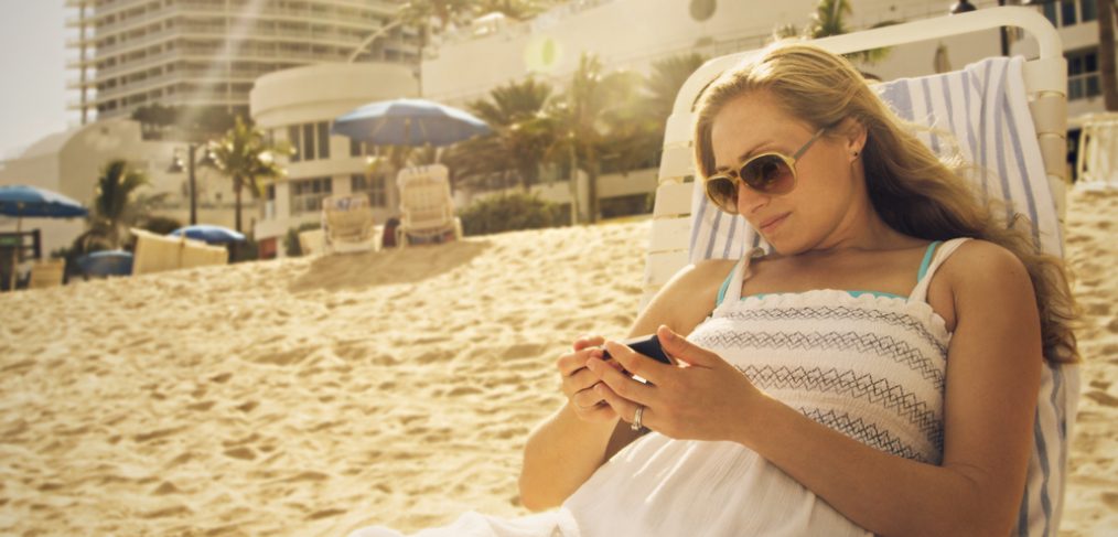 Woman looking at her phone in a beach.