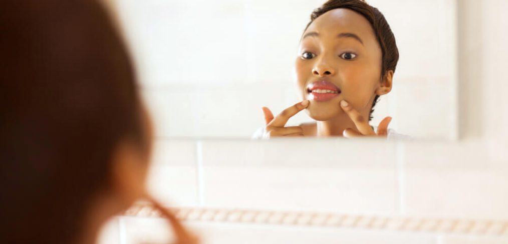 Woman looking at her skin in bathroom mirror