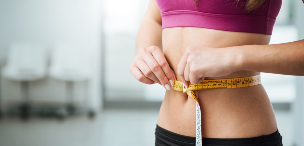 Woman measuring waist with tape measure