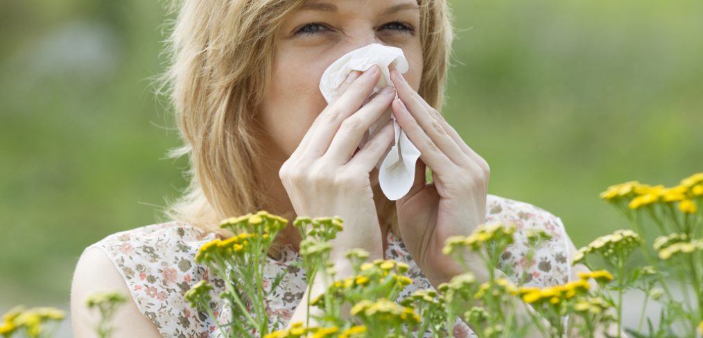 Woman sneezing into napkin outside