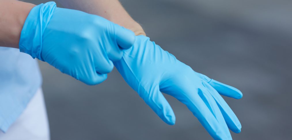 Putting on blue latex gloves