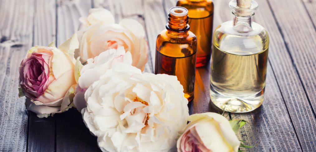 Vials of botanical oils surrounded by flowers