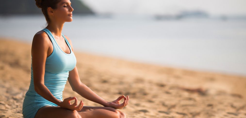 Woman meditating on the beach