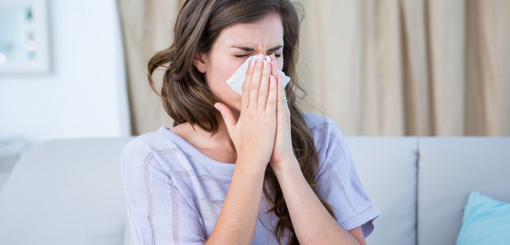 Woman sneezing into napkin