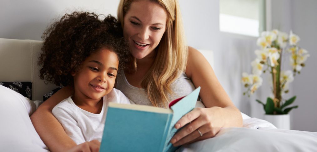 Woman reading bedtime story to child in bed