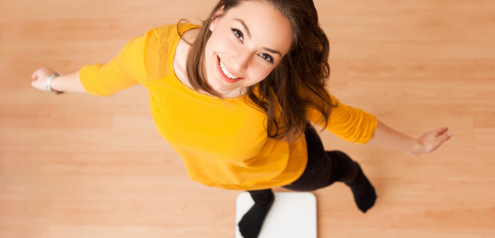 Smiling woman standing on weighing scale