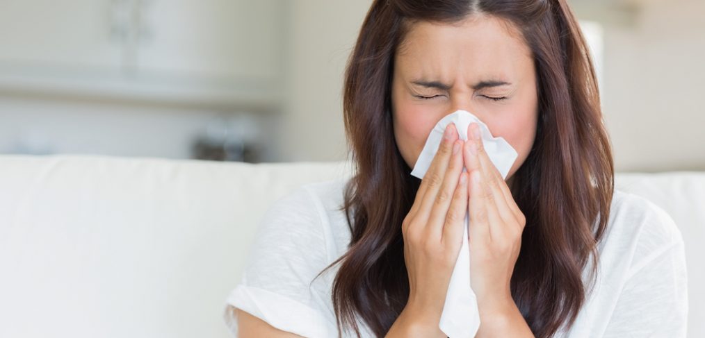 Woman sneezing into napkin