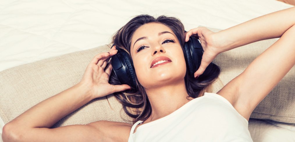 Woman with headphones on the bed