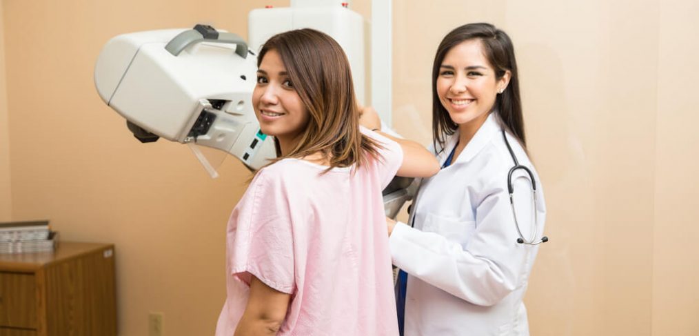 Smiling woman undergoing mammography