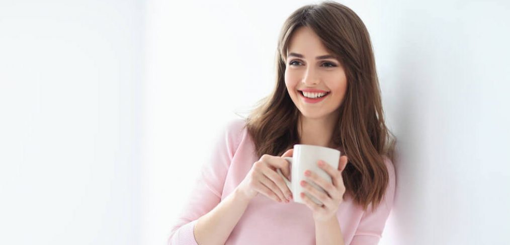 Smiling woman nursing a cup of tea