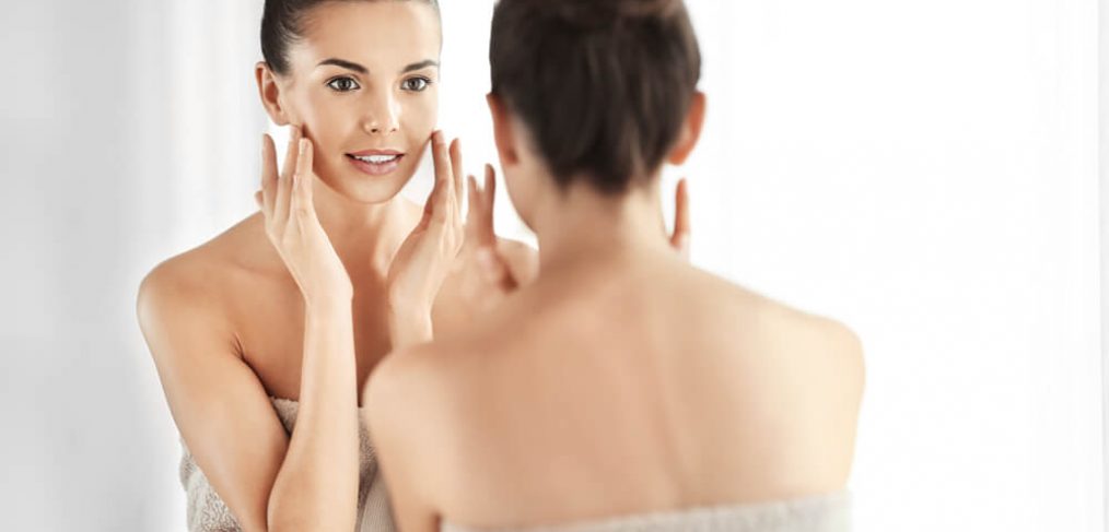 Woman checking skin in mirror