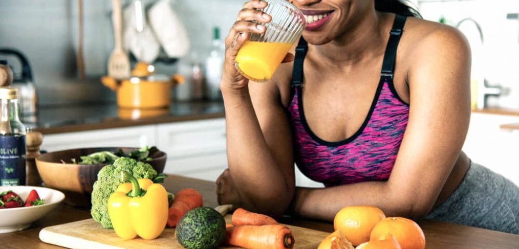 Athletic woman enjoying a glass of orange juice in the kitchen