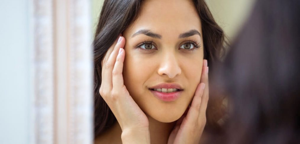 Young beautiful woman looking in the mirror