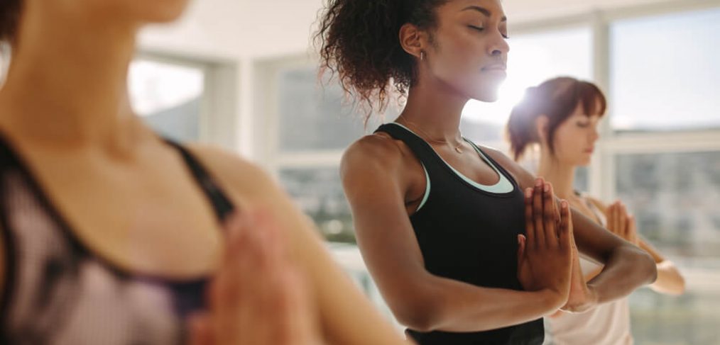 Three women clasping their hands together, in a gym setting