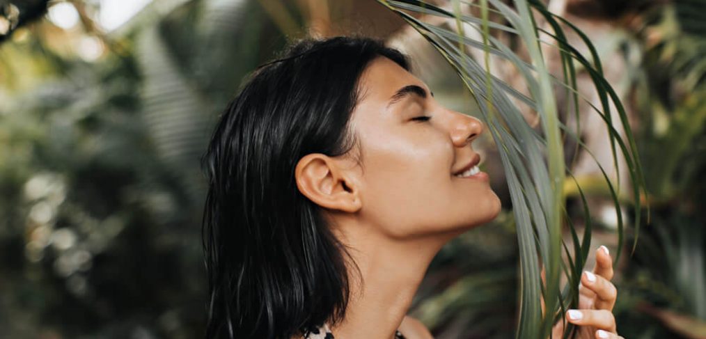 Woman enjoying the scent of a palm leaf