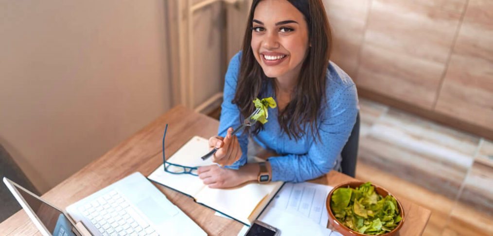Woman enjoying a salad while working on her laptop